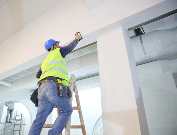 Painter applying fresh coat of paint on wall