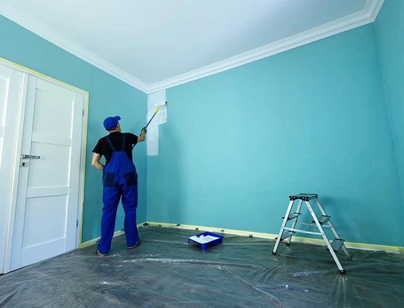 A painter applying a fresh coat of paint on a wall with a roller