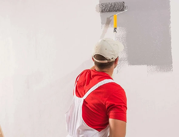 A painter carefully applying a fresh coat of paint on the wall with a roller
